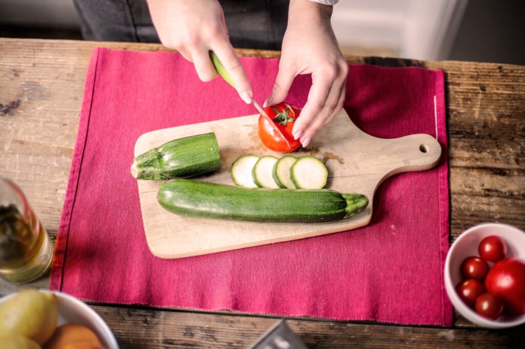 person-slicing-tomato-on-chopping-board-