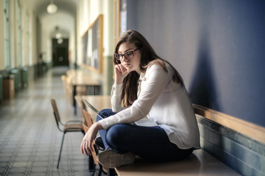 woman-in-white-long-sleeve-shirt-and-blue-denim-jeans-sitting-on-table-