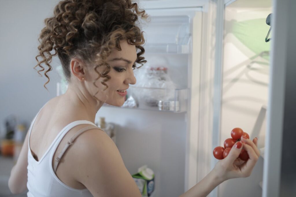 smiling-woman-with-sprig-of-ripe-red-grape-in-kitchen