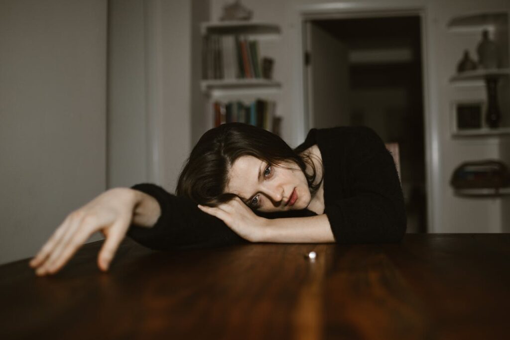 woman-resting-her-head-on-a-wooden-table