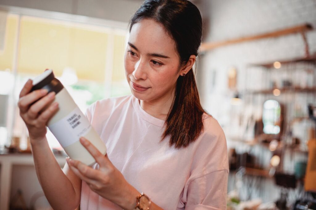 crop-asian-female-buyer-watching-beauty-product-in-shop-