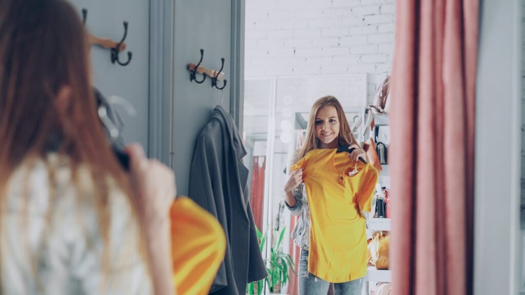 woman-trying-on-yellow-top-in-fashion-boutique