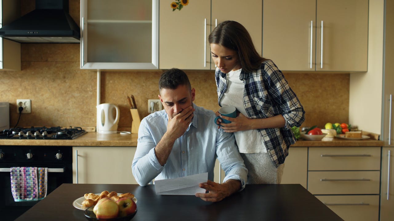 couple-reading-financial-document-in-kitchen