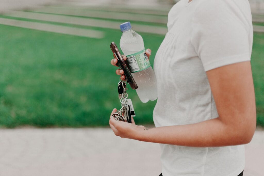 /person-holding-car-keys-and-bottled-water-
