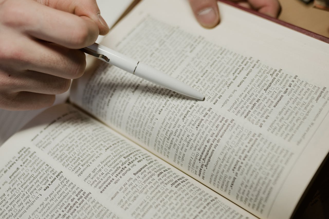 shot-of-a-person-pointing-a-pen-on-a-book