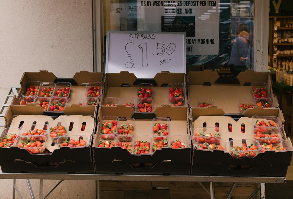 8 Foods That Completely Ruined My Grocery Budget 4 Plastic containers of strawberries for sale at a market stall, priced at £1.50 each.
