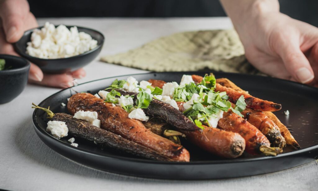 Plate of roasted carrots garnished with cheese and parsley, perfect for a healthy low-carb meal.