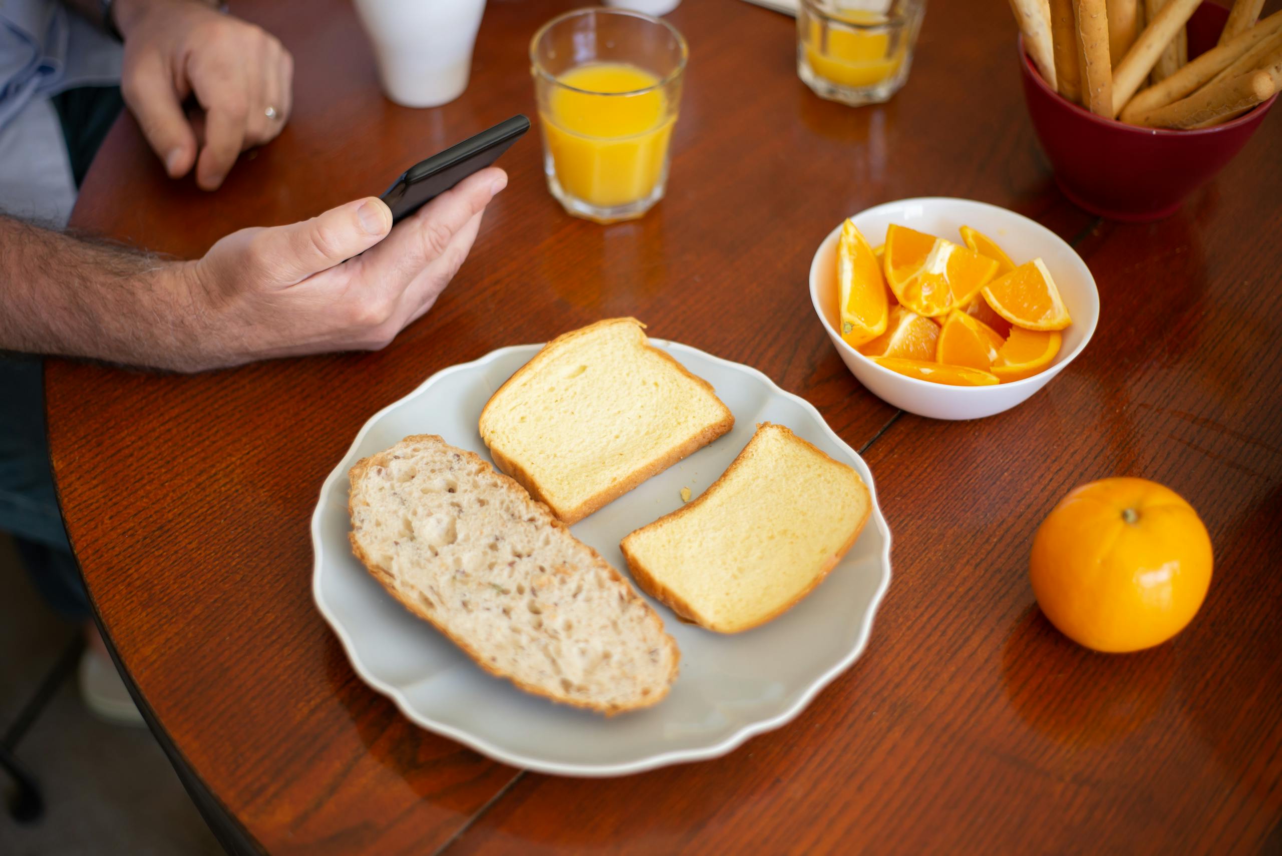 Plate with assorted bread and a bowl of orange slices on a breakfast table in Portugal.