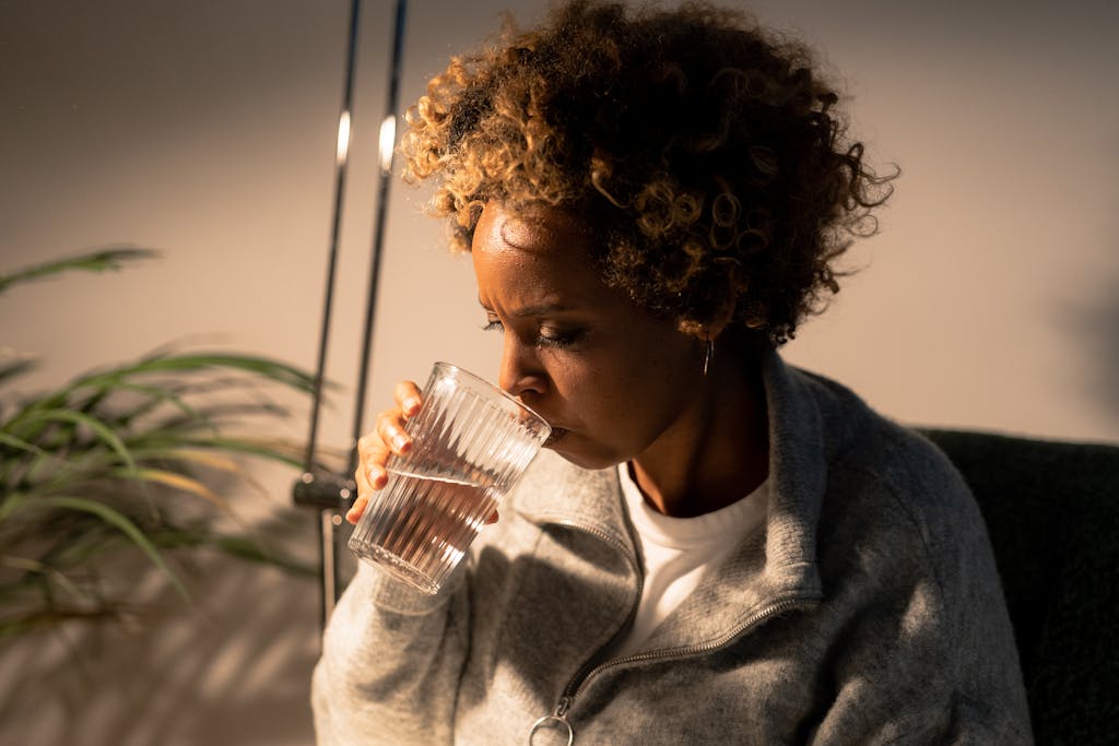 Ignore These 8 Hacks and Your Mornings Will Turn Chaotic and Stressful 3 Portrait of an African American woman savoring a refreshing glass of water indoors.