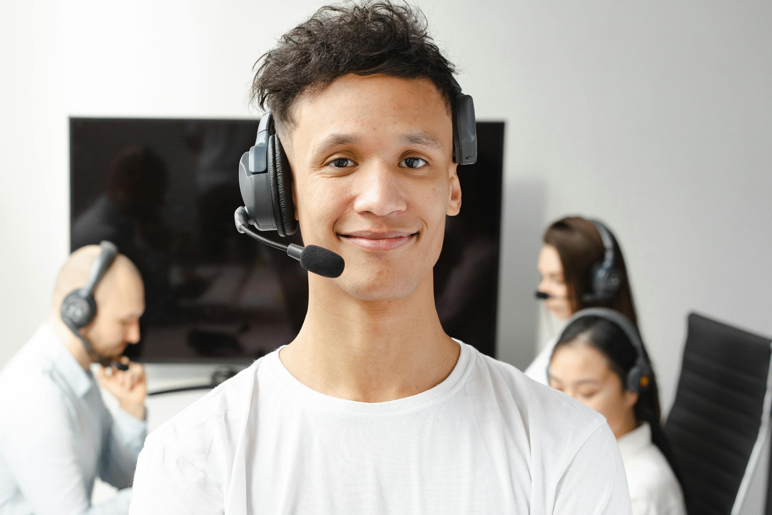 Professional call center agent wearing a headset, smiling confidently in a modern office setting.