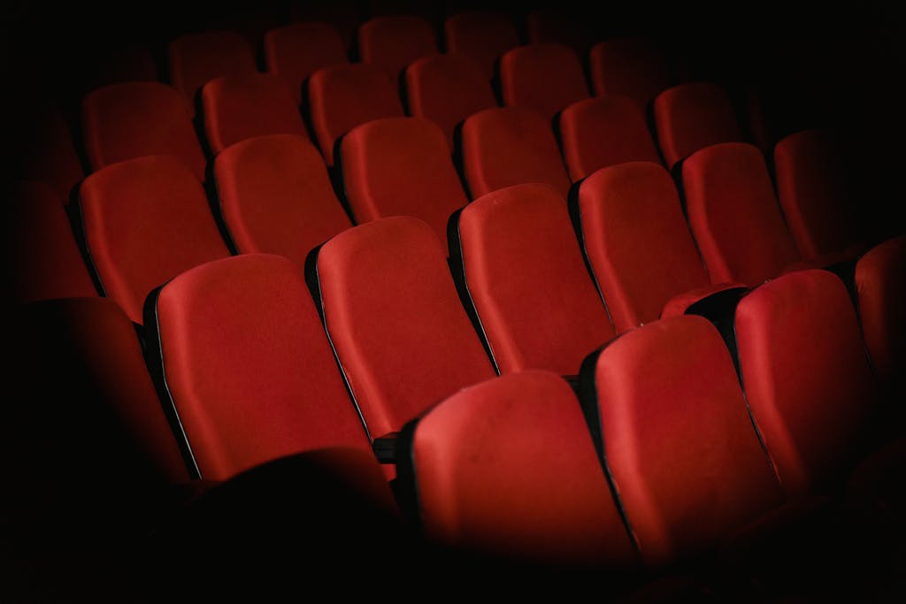 8 Things Baby Boomers Had That the Modern World Destroyed 2 Rows of empty red armchairs in a dimly lit cinema setting, creating a moody atmosphere.