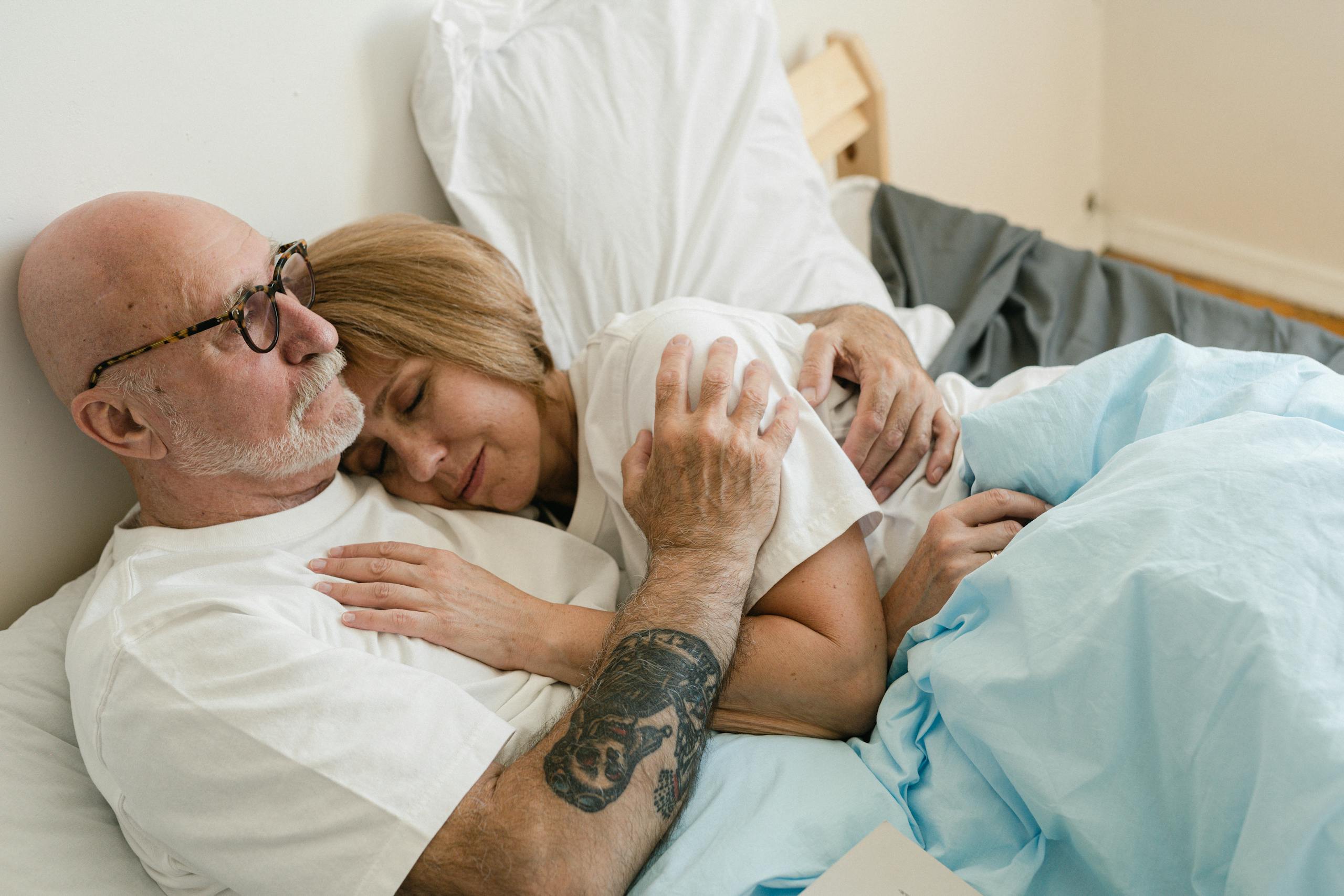 Senior couple embracing in bed, showcasing love and togetherness.