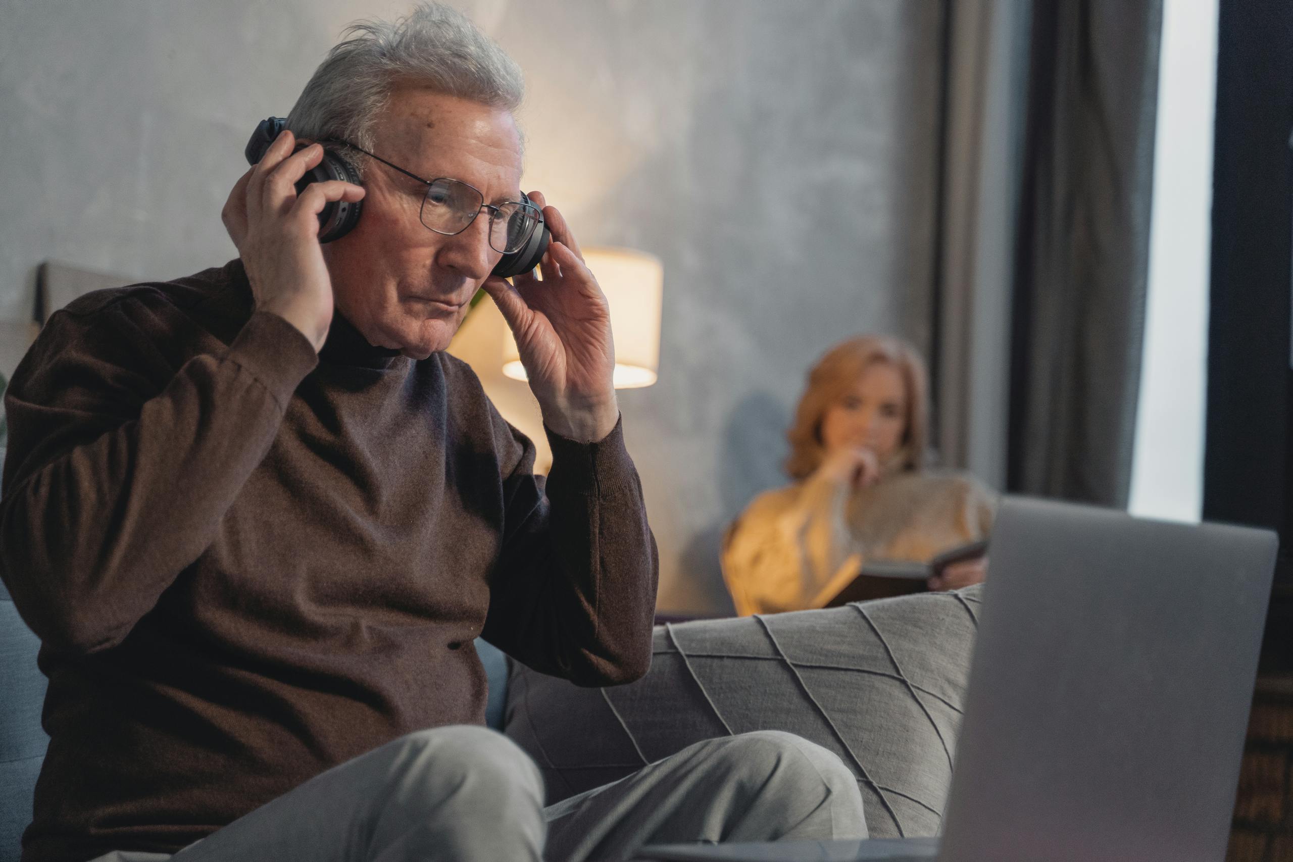 Senior man wearing headset working from home, laptop use for online communication.