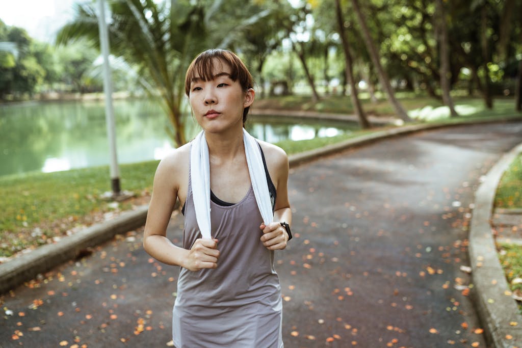 Avoid These 8 Heat Wave Mistakes Before They Harm Your Health 4 Serious ethnic female athlete wearing sportswear and smart watch looking away while jogging alone in park at daytime in summer day