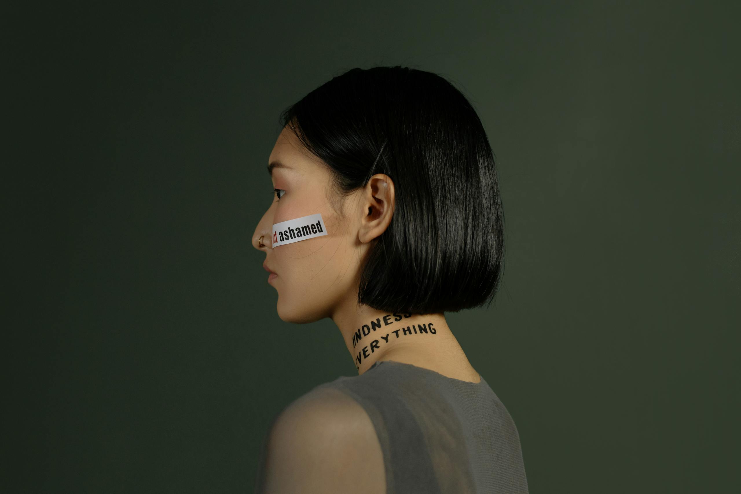 Side view of a young woman with words on her face and neck, symbolizing freedom and choice.
