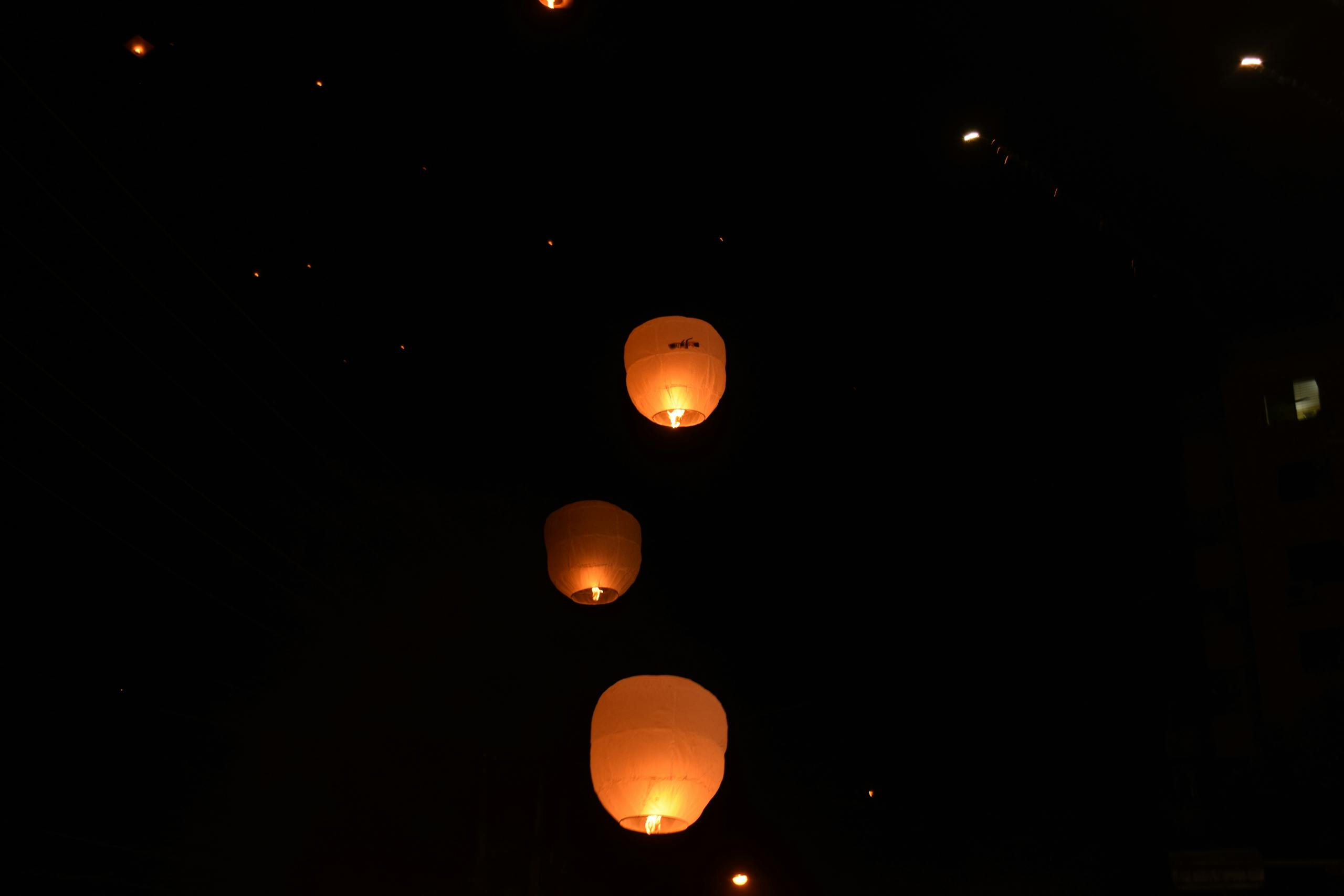 Sky lanterns glowing warmly as they ascend into the night sky.