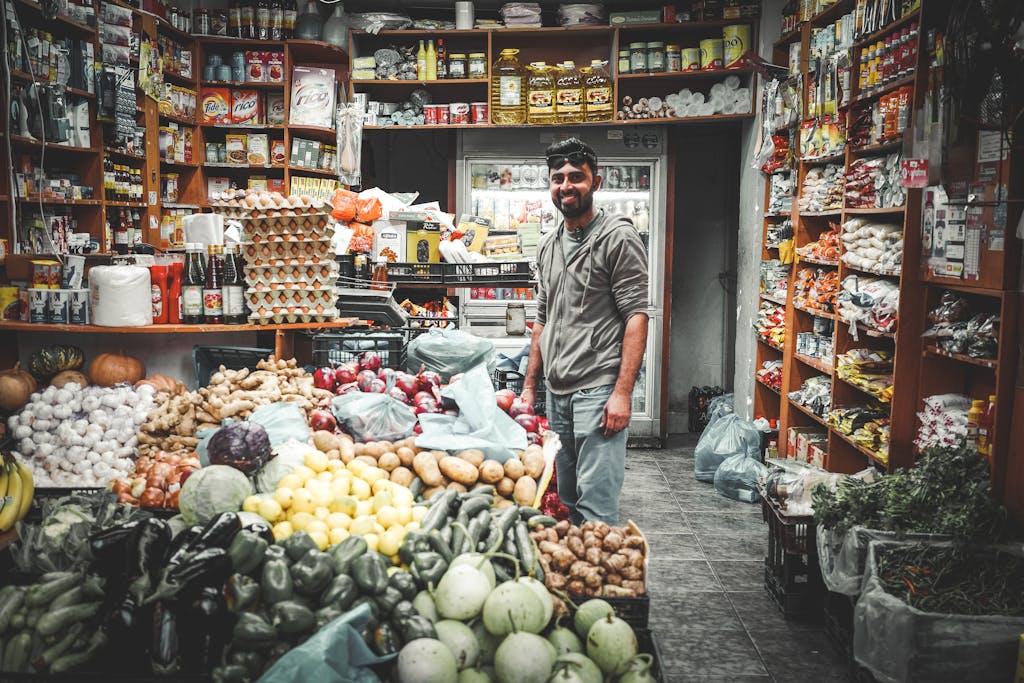 Smiling man in Athenian grocery store surrounded by colorful fruits and vegetables.