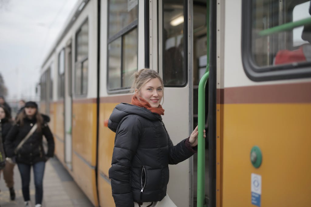 Smiling woman in warm clothes boards tram during winter in the city.
