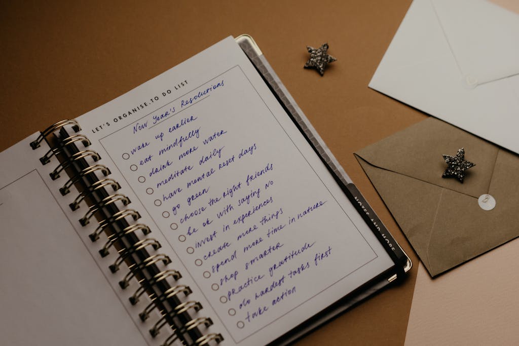 Spiral planner open to a page with handwritten New Year's resolutions and envelopes nearby.