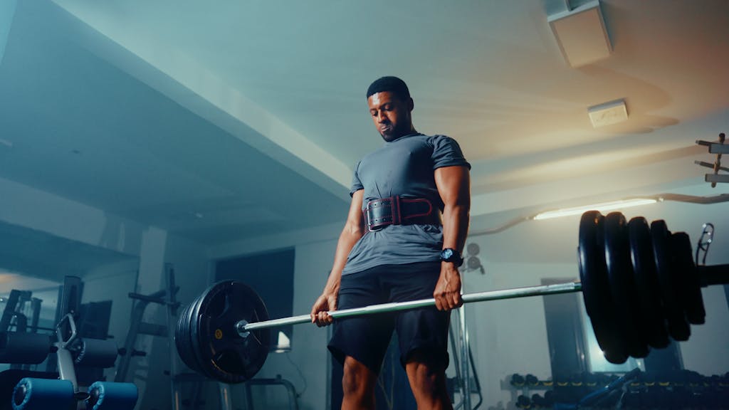 Strong muscular man performing deadlift exercise in a modern gym.