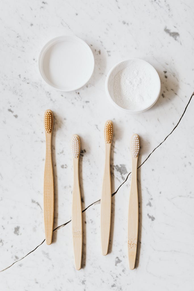 Top view layout of different various wooden brushes and tooth powder placed on chipped marble table