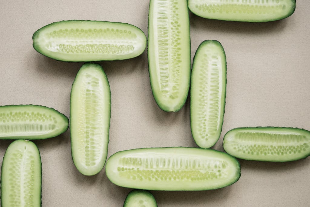 Top view of fresh sliced cucumbers arranged on a neutral background, showcasing their vibrant freshness.