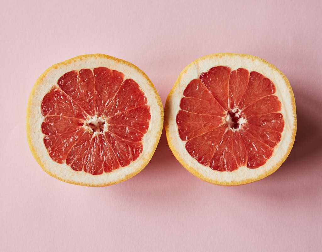 Top view of fresh sliced juicy grapefruit placed on pink background in studio