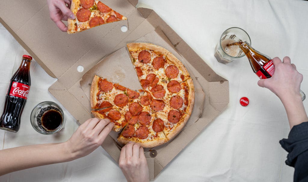 Stop Eating These 8 Fast Foods Before They Damage Your Blood Sugar 3 Top view of friends sharing pepperoni pizza and enjoying Coca Cola.