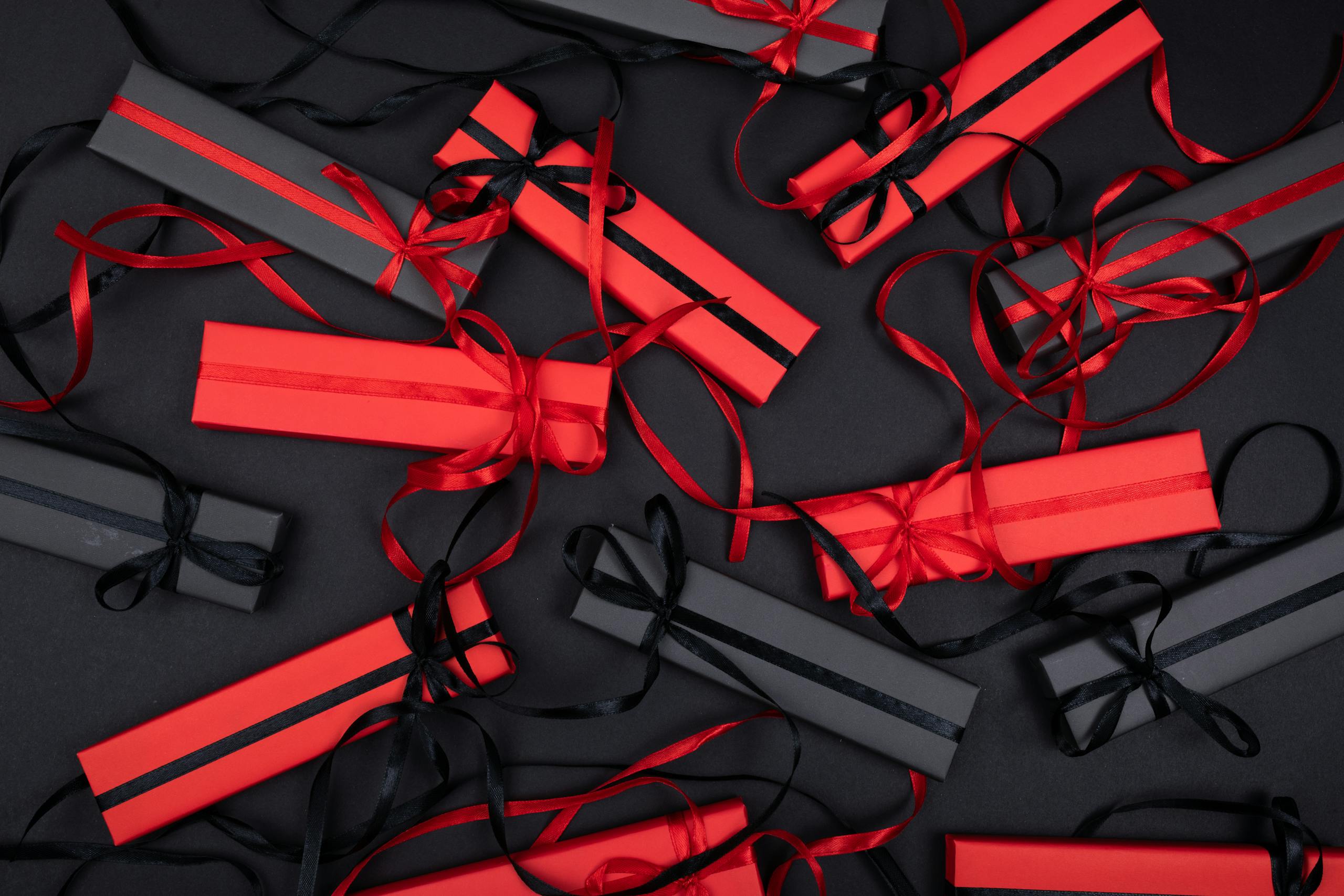 Top view of stylish black and red gift boxes with ribbons on a dark background, perfect for holiday celebrations.