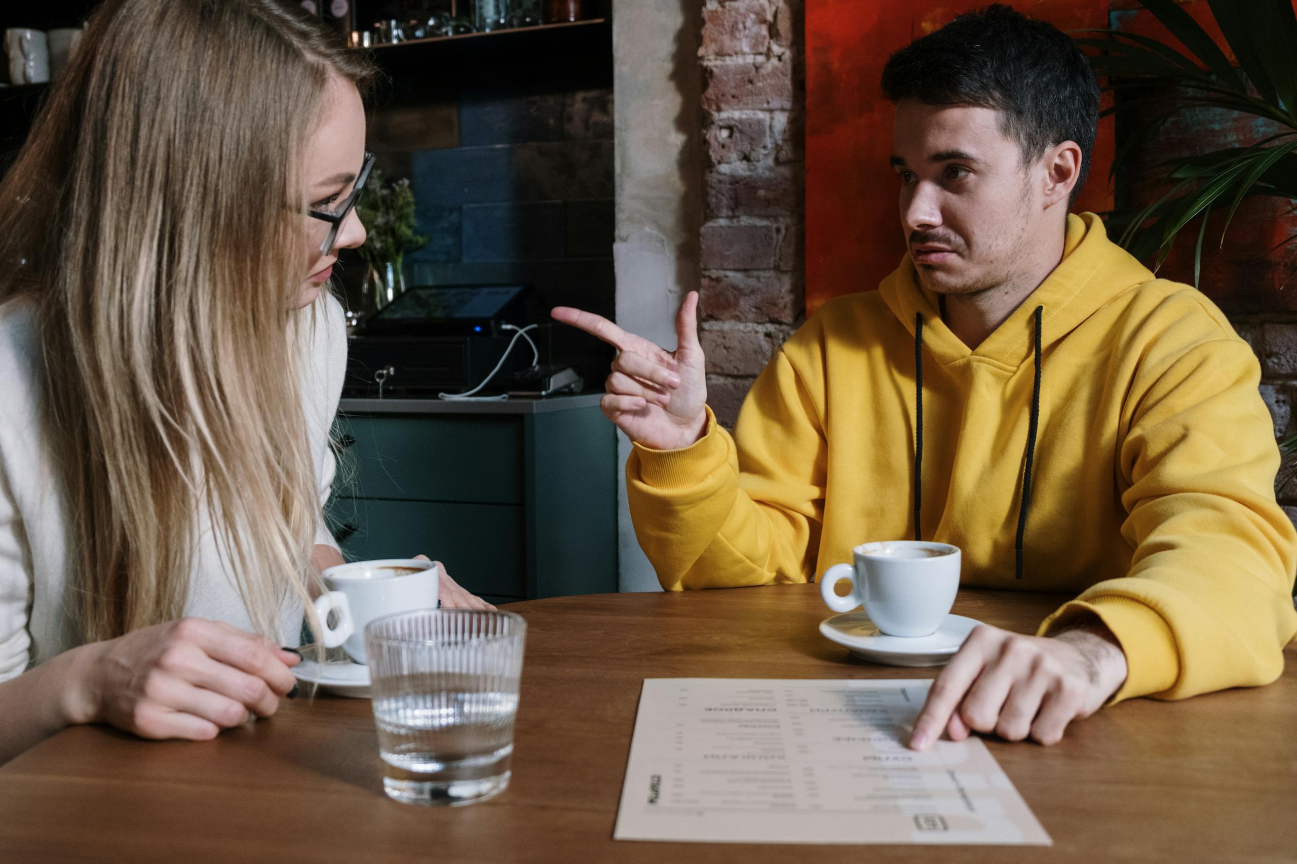 Two adults discussing over coffee and a menu at an urban cafe.