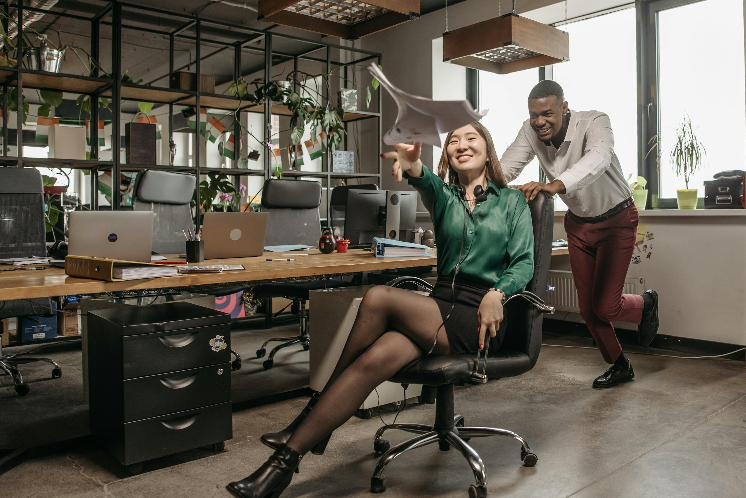 Two colleagues enjoy a fun moment at the office, embodying teamwork and joy.