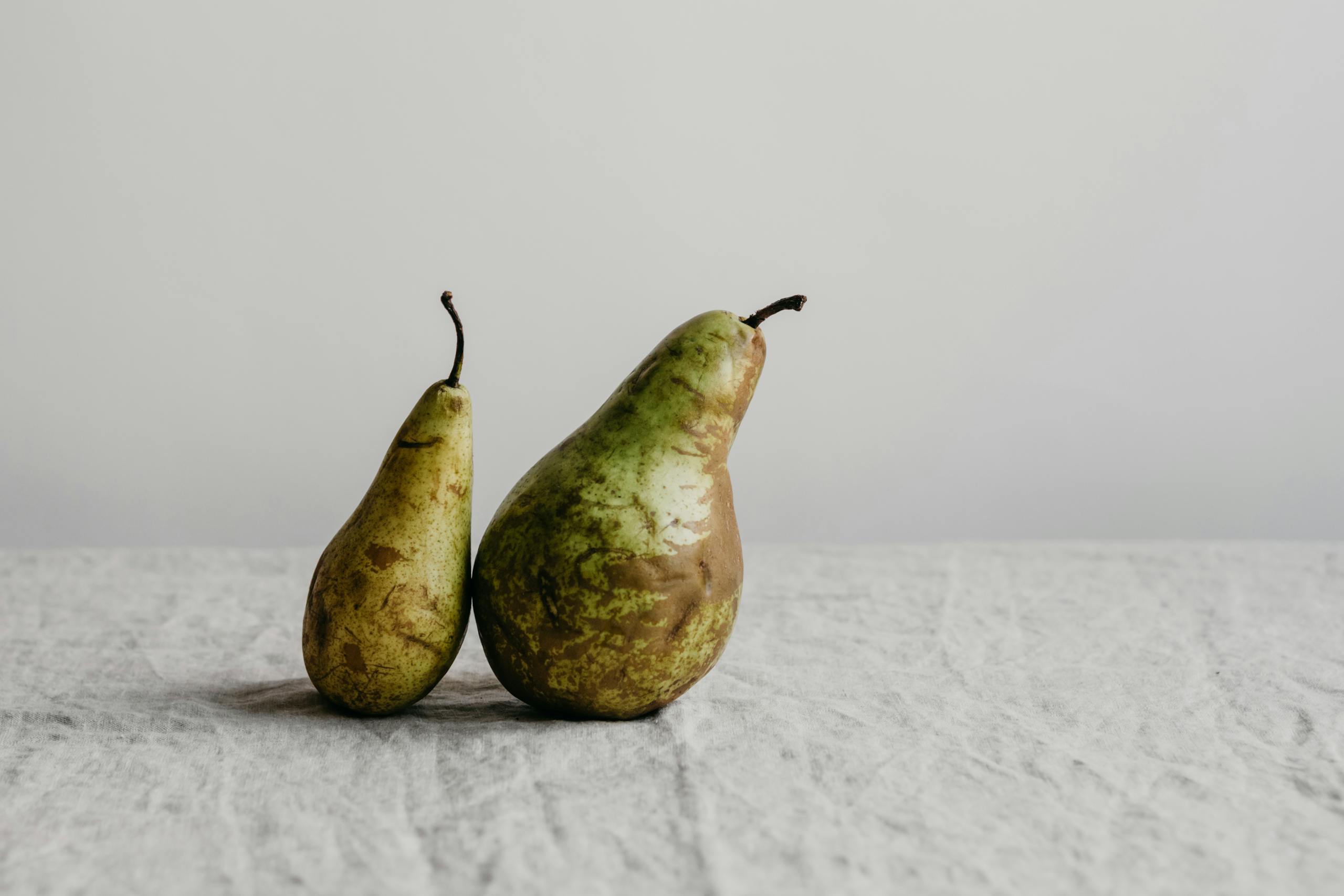 Two ripe pears on textured cloth against a minimalist white background. Perfect for food photography.