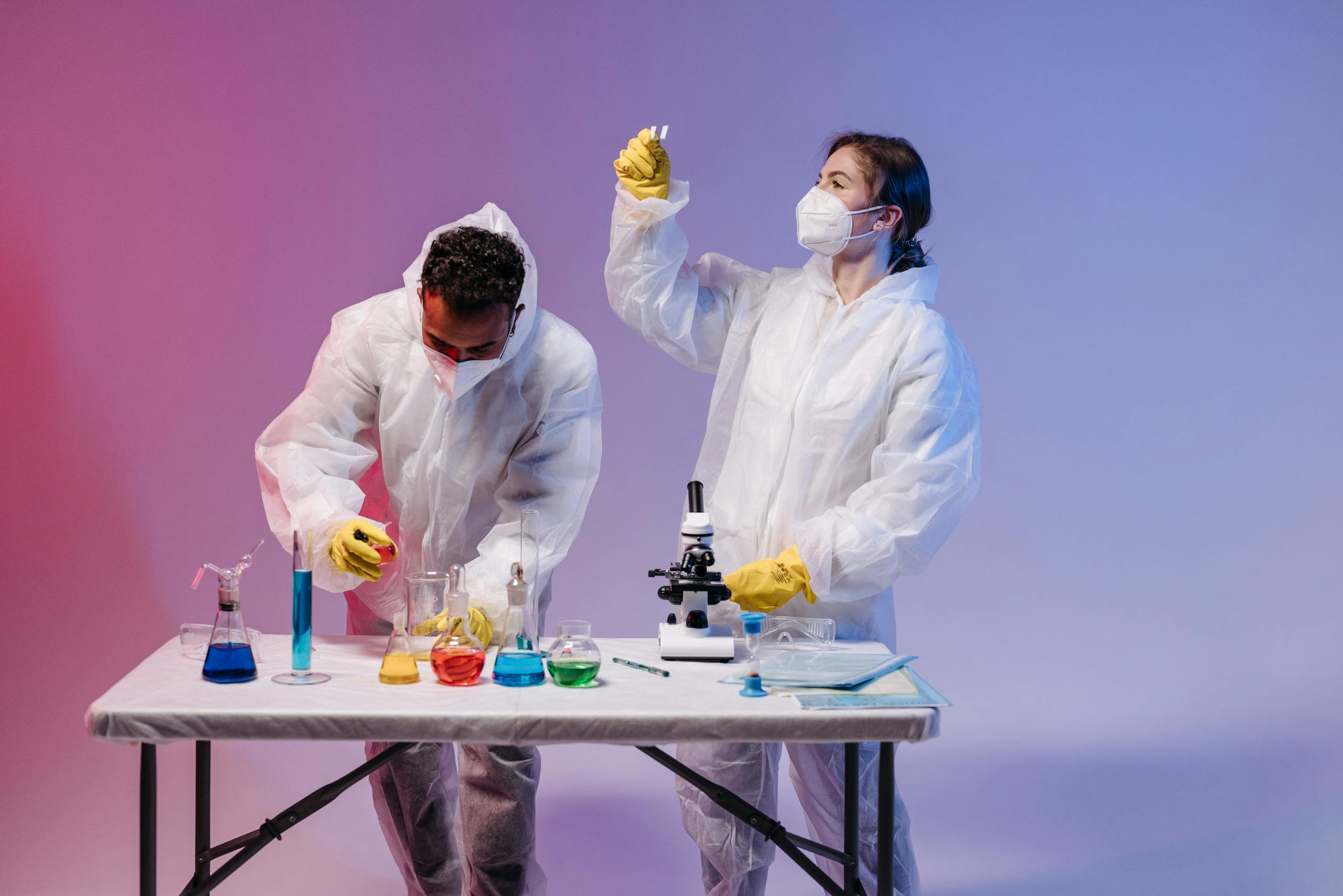 Two scientists in protective gear conducting experiments with colorful chemicals in a lab.