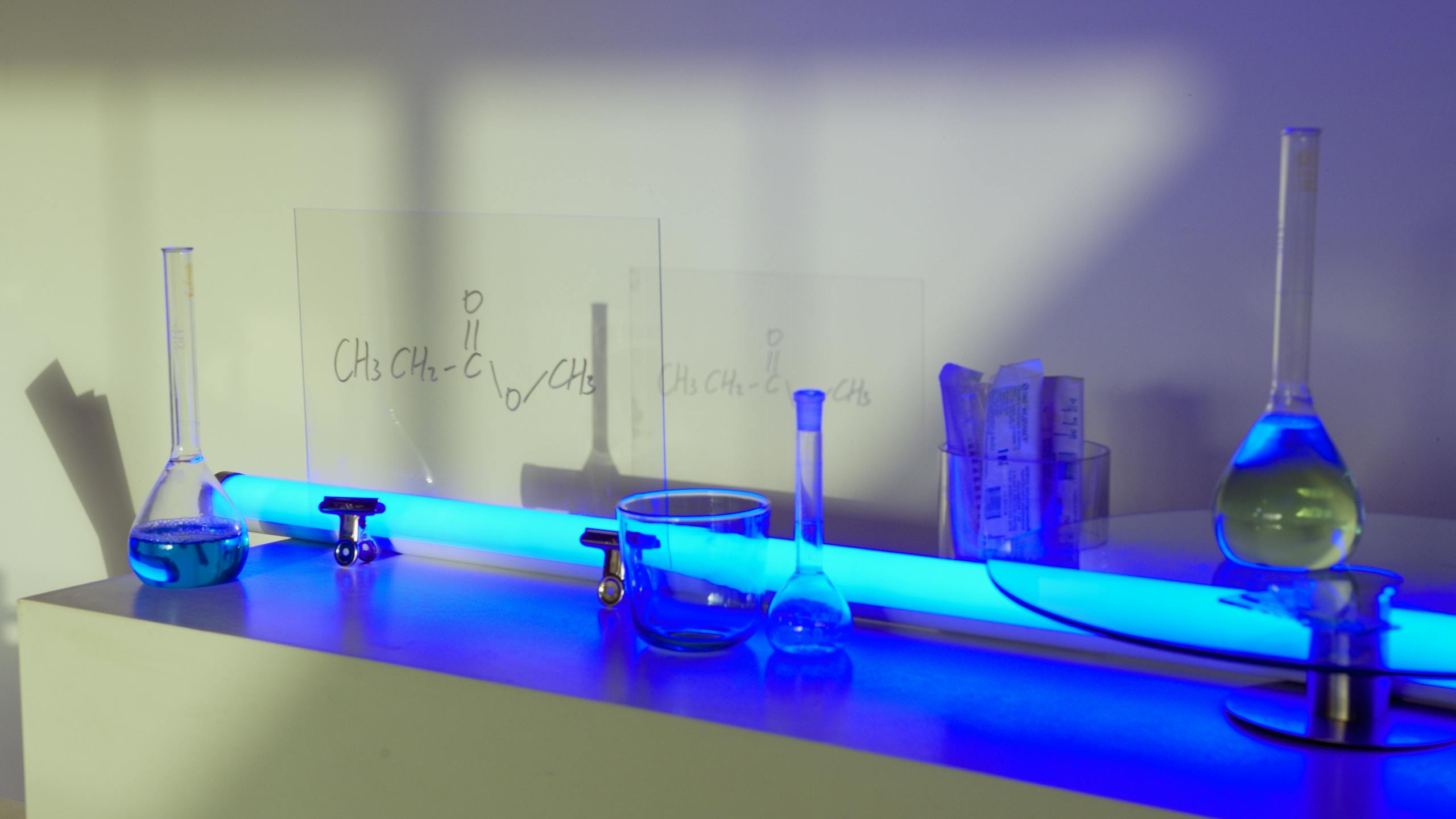 Various glass flasks and equipment in a lab with blue lighting ambiance.