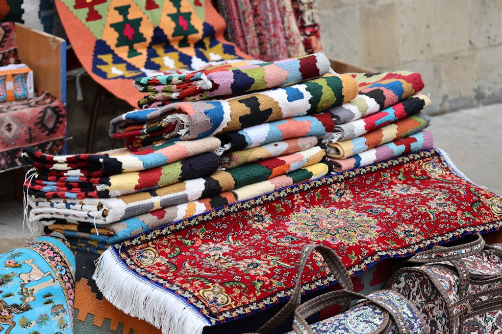 Vibrant and diverse traditional woven rugs displayed in an outdoor market setting.