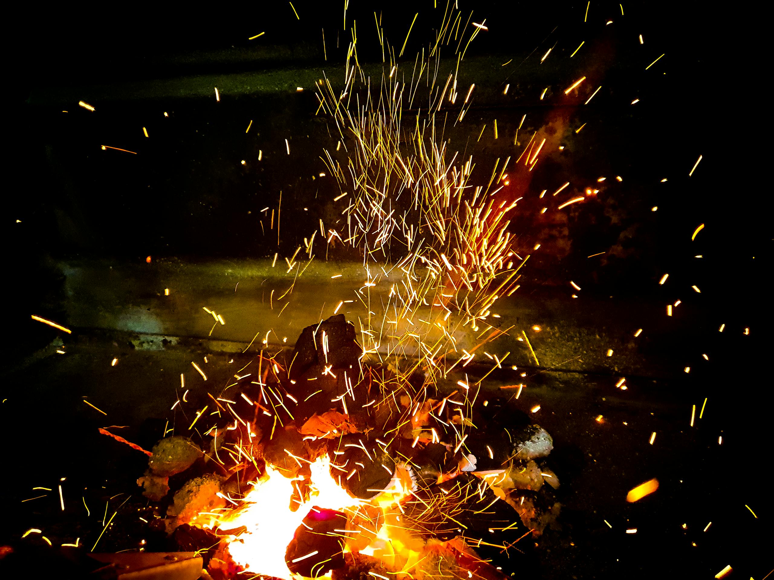 Vivid flames and sparks from burning wood create a dynamic fire scene, highlighting warmth and energy.