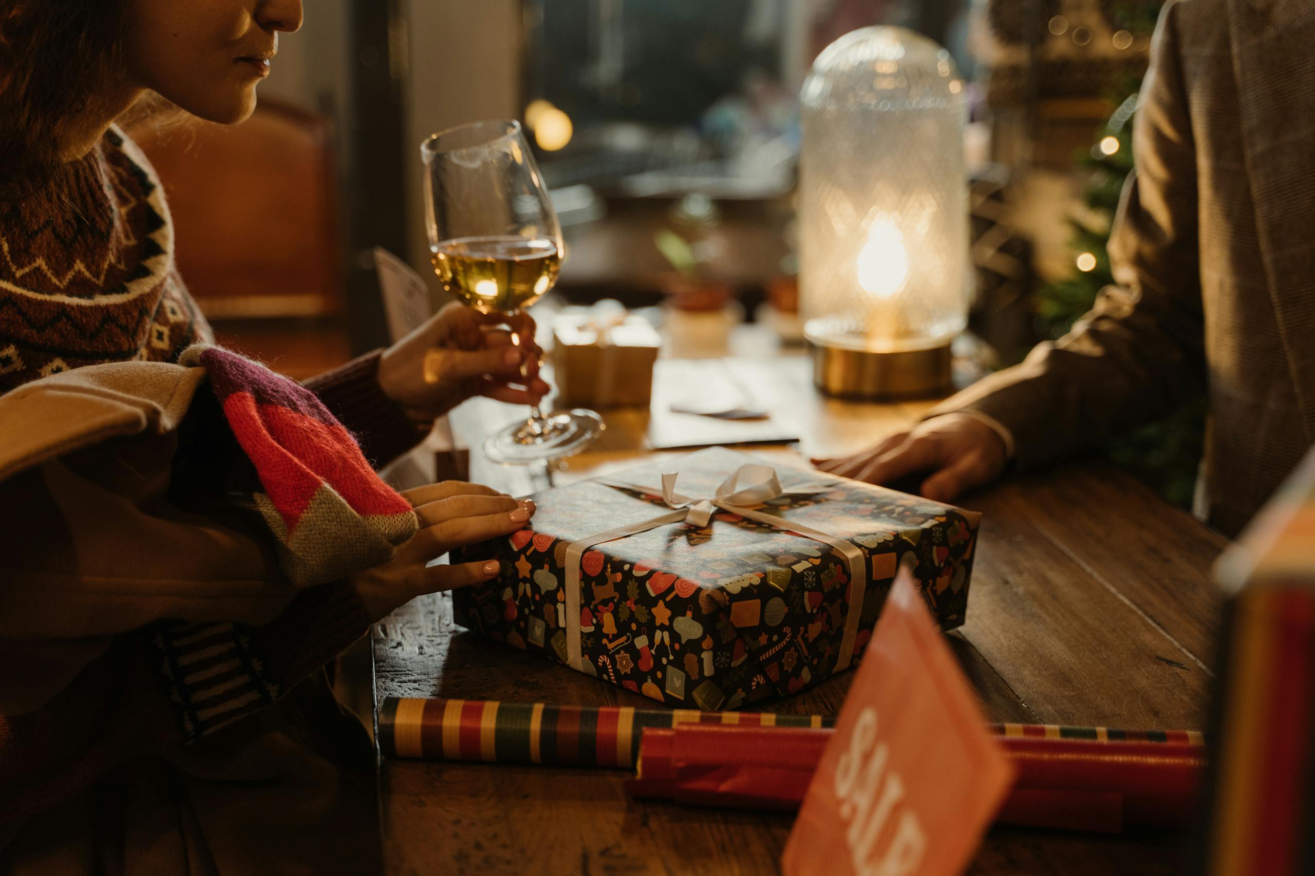 Warm holiday atmosphere with gift exchange and wine, perfect for festive moments.