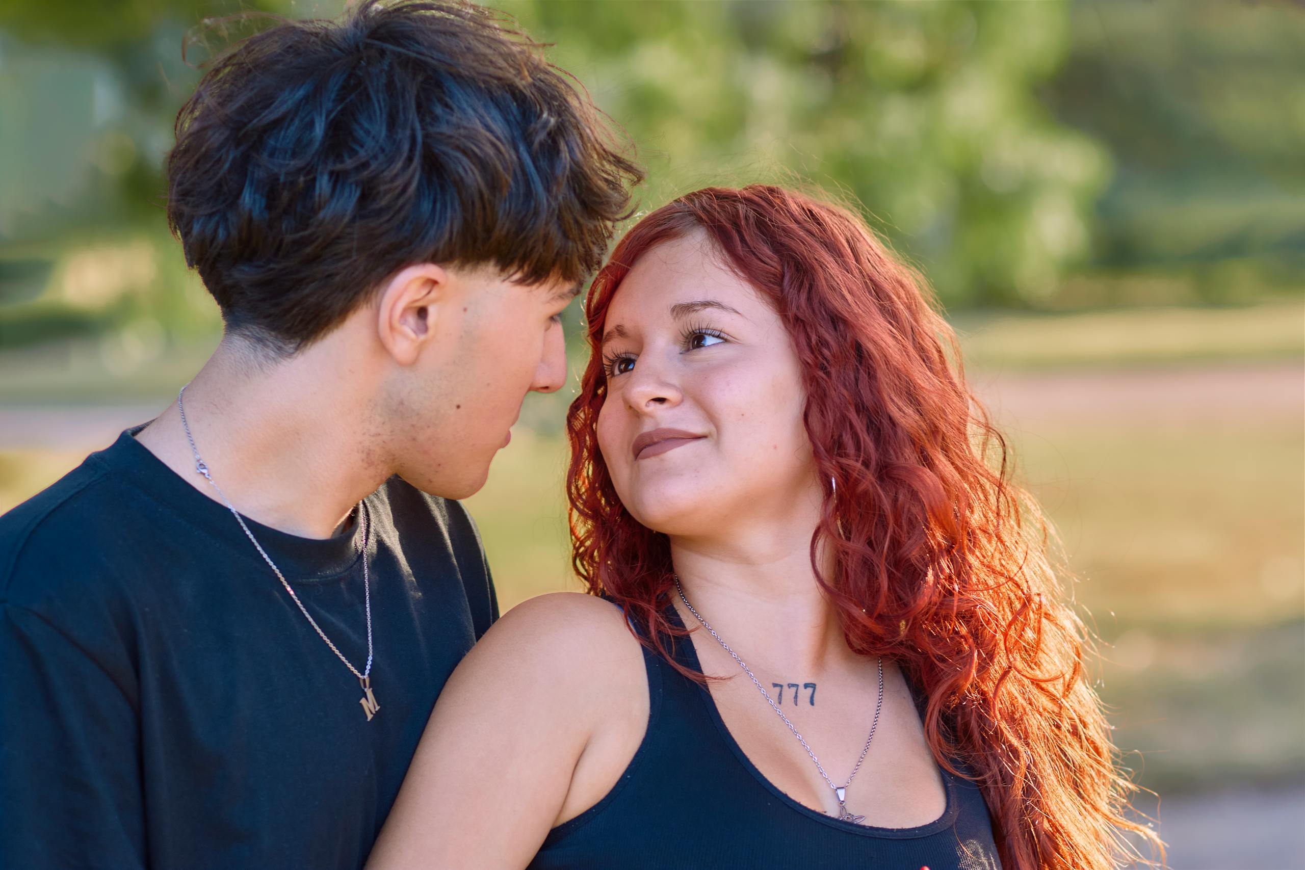 Young couple sharing a tender moment outdoors on a bright sunny day.
