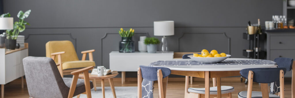 Yellow citruses on dining table in grey open space interior with wooden armchair