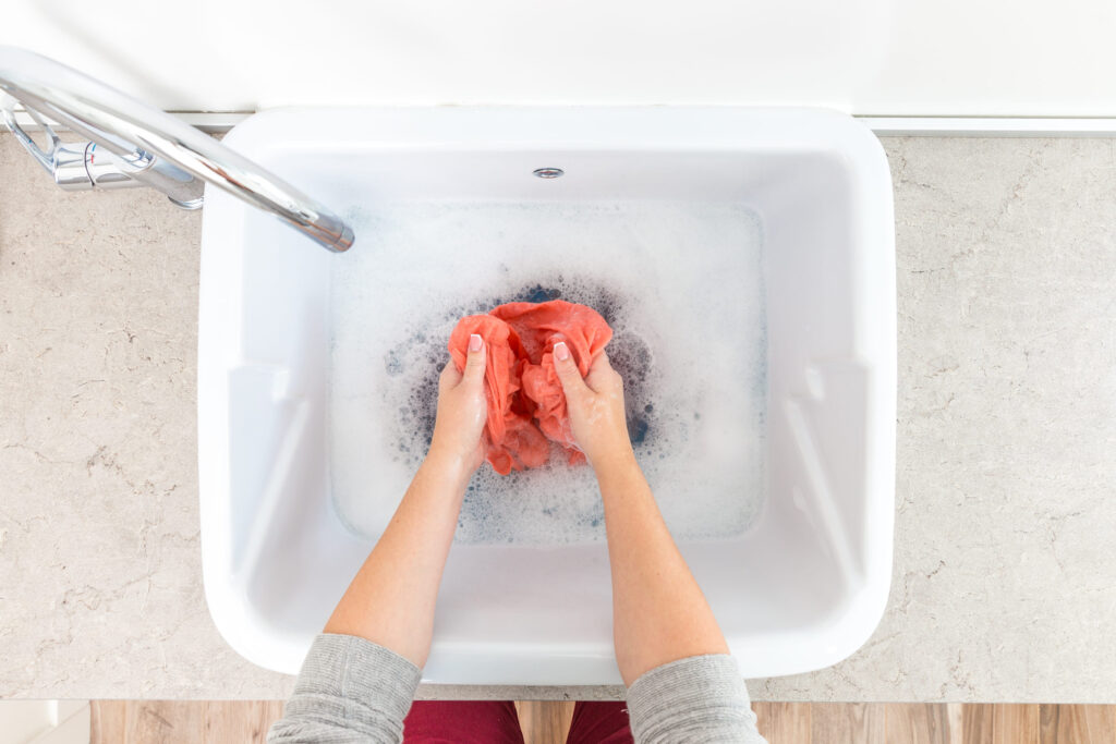 Female hands washing color clothes in sink