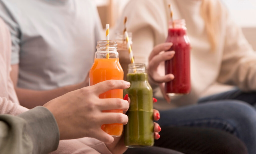 Unrecognizable women drinking colored healthy detox smoothie at home, panorama, blurred background