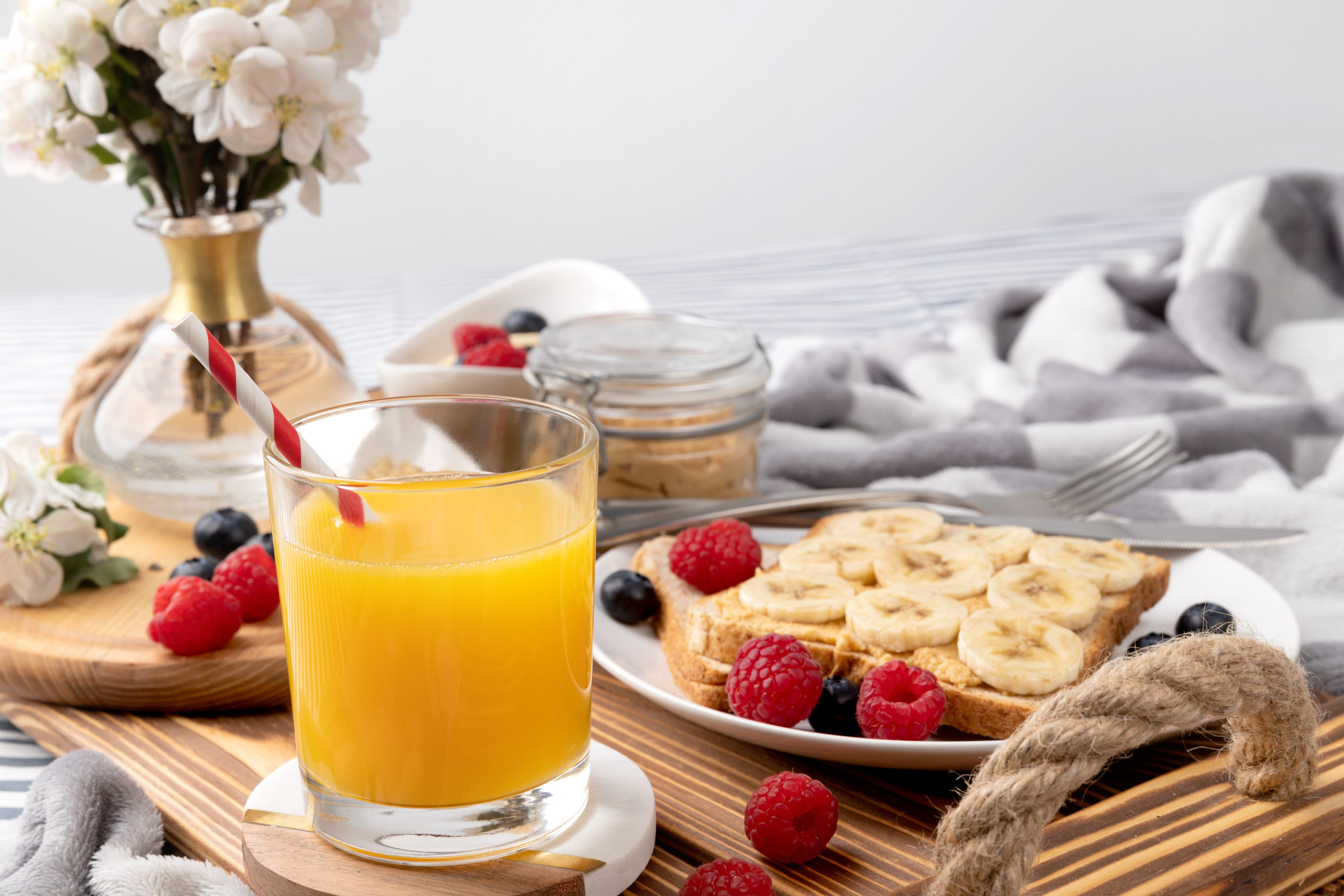 Breakfast in bed. Wooden tray with glass of orange juice and sandwich with berries. Morning healthy homemade breakfast