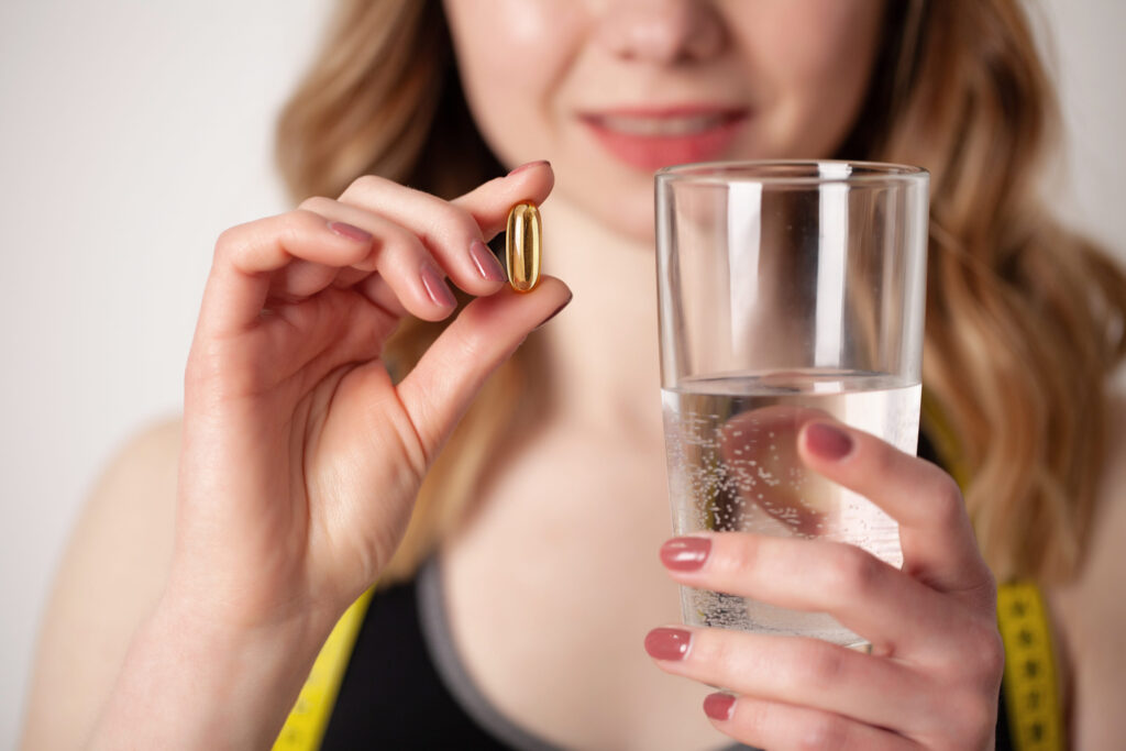 Portrait of smiling young woman with Omega 3 fish oil capsule