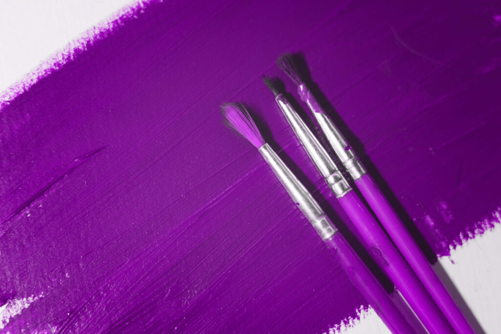 Purple colored paper with three brushes on it. Abstract background for your projects. Selective focus.