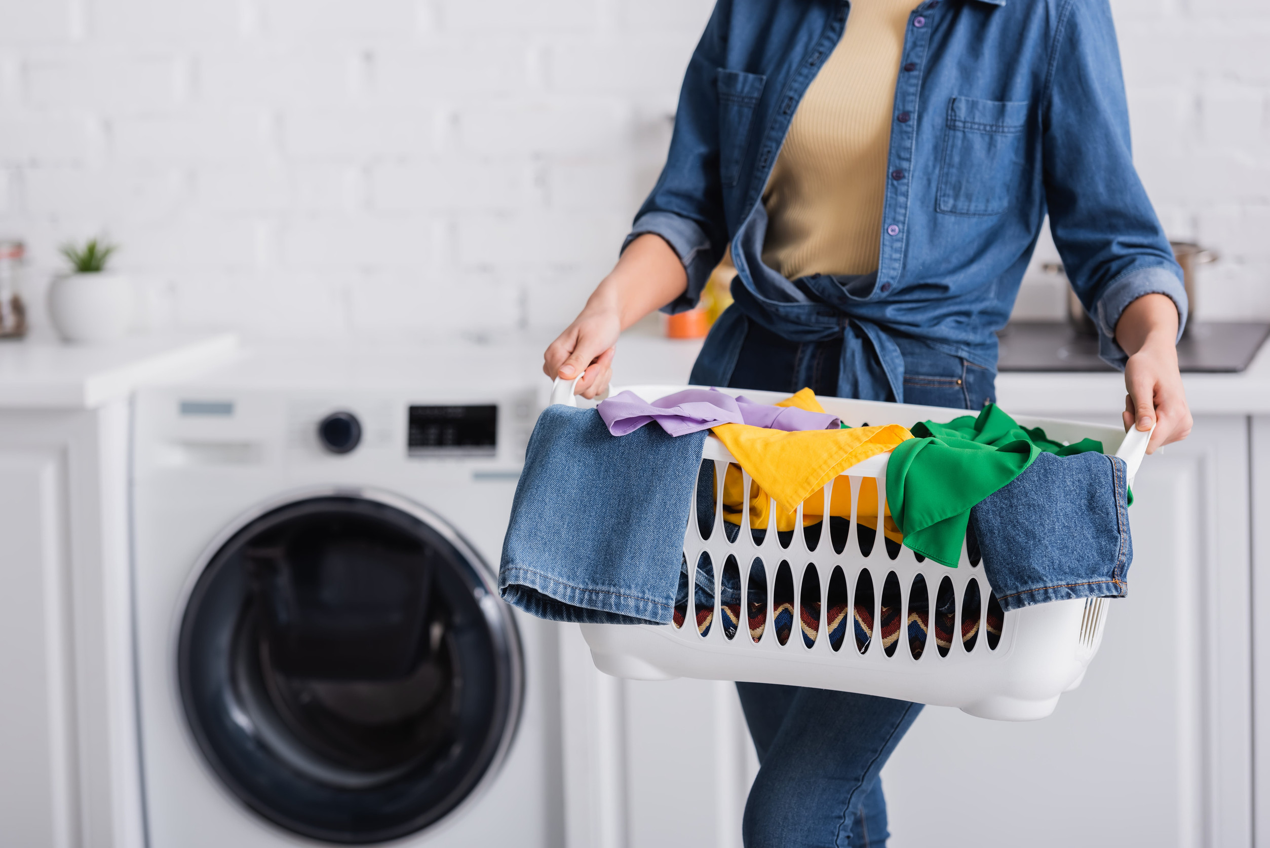 Cropped view of housewife holding basket with clothes at home
