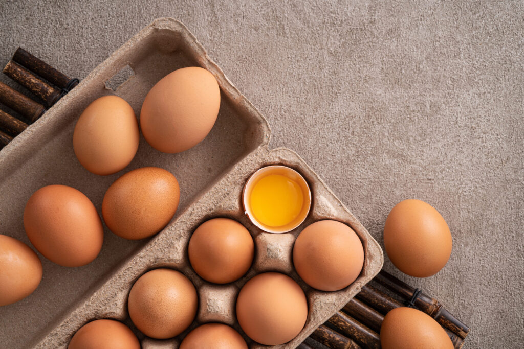 Top view of fresh brown chicken eggs in a plate on gray table background.