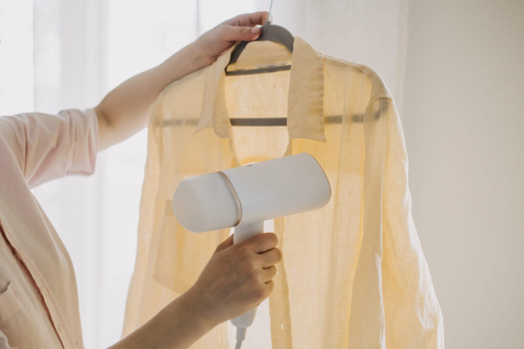 Woman Using Steamer to Remove Wrinkles from Shirt