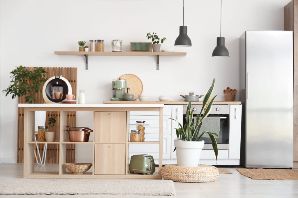 Interior of stylish kitchen with island table, houseplants and modern refrigerator