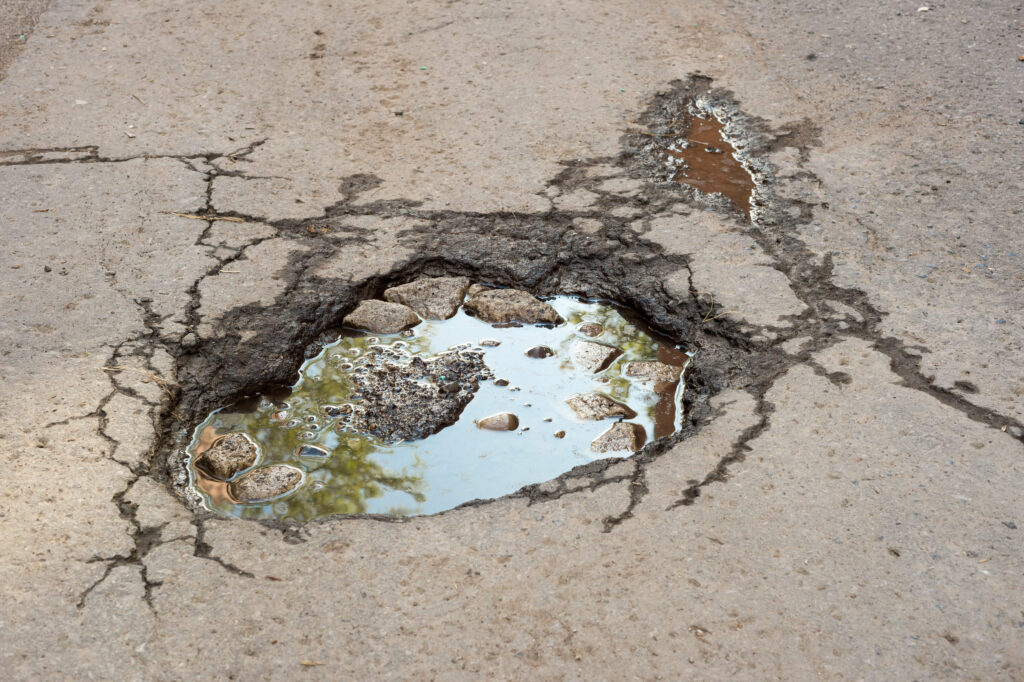 Large deep pothole with blue sky reflection in Montreal street, Canada.
