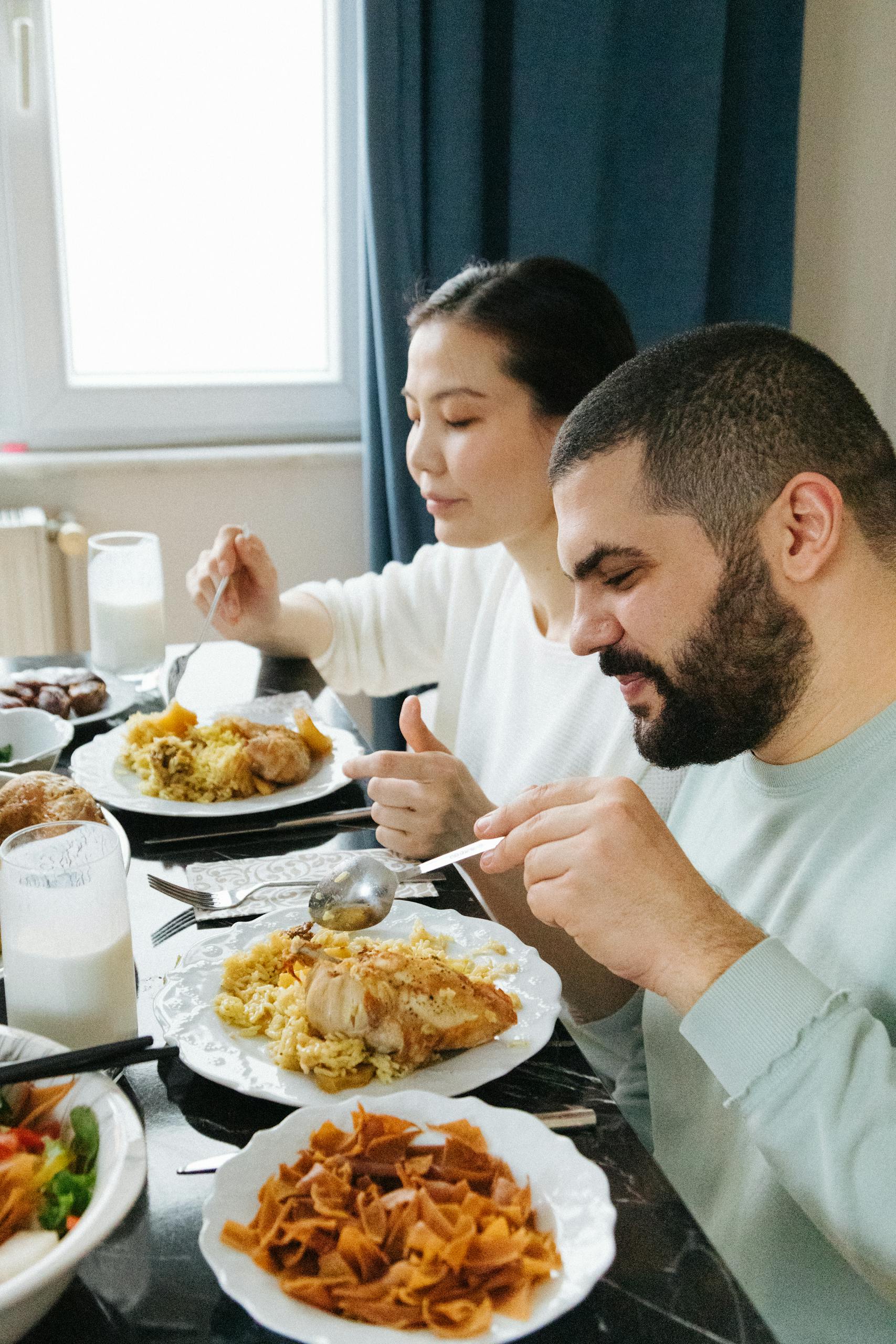 A couple enjoys a traditional meal at home, sharing a peaceful moment together.